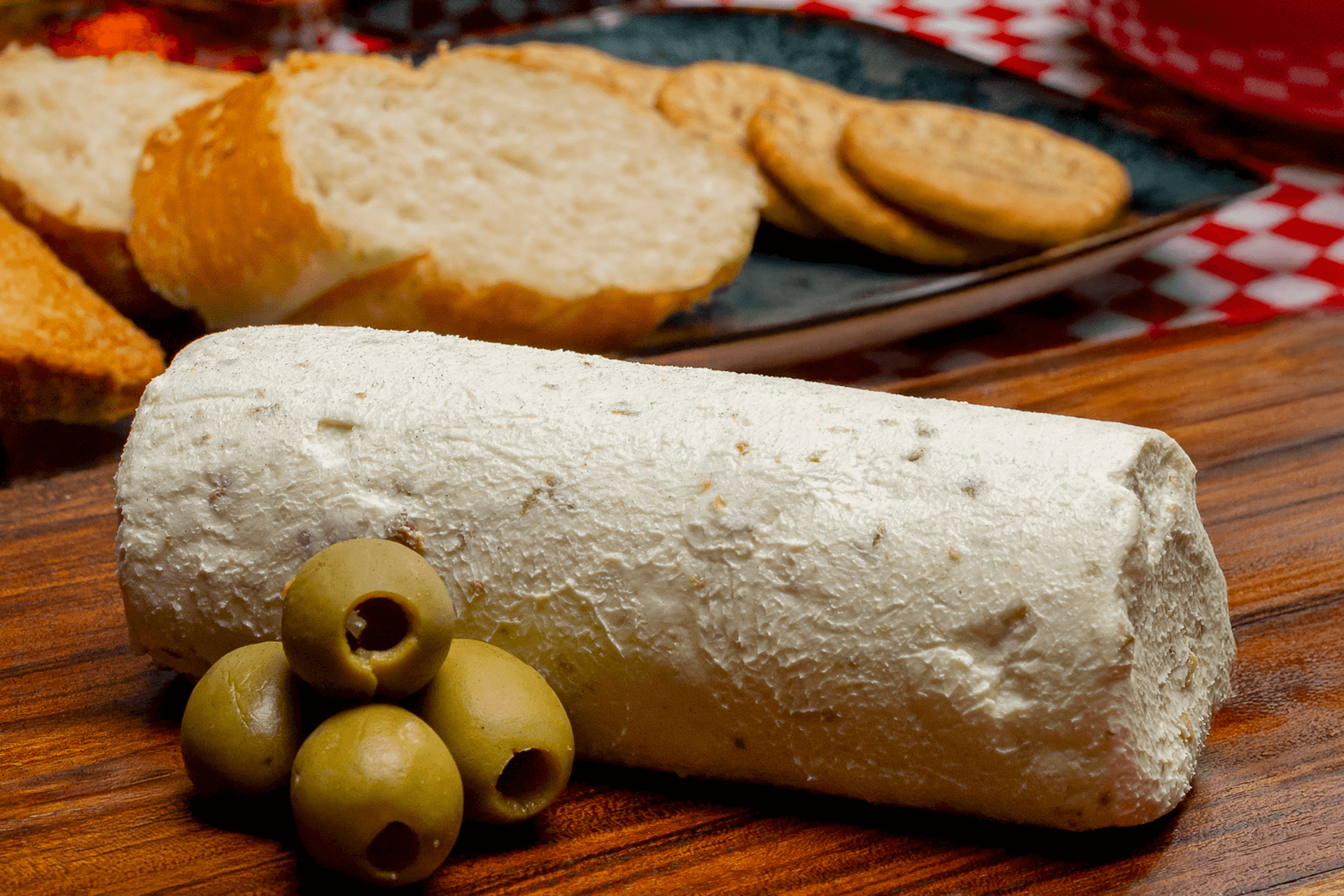 Medallones de queso de cabra Le Blanc con aceituna listos para servir, enfatizando la integración de ingredientes naturales y su presentación sofisticada.